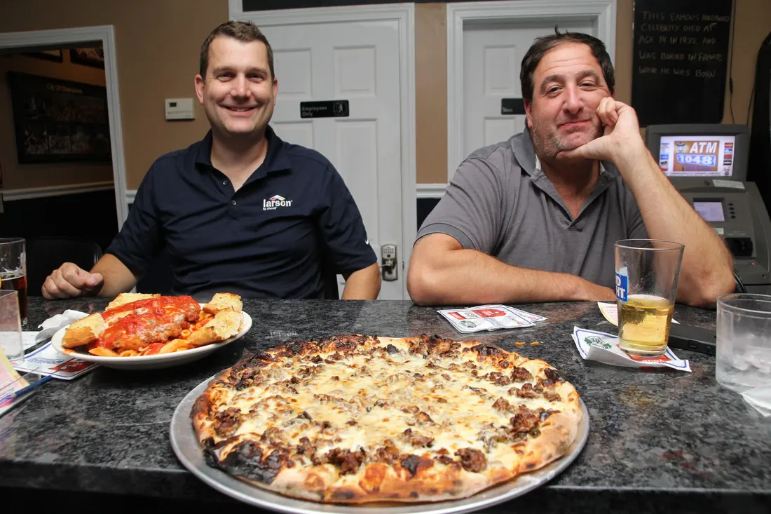 Pizza and a plate of pasta on a table at 1048